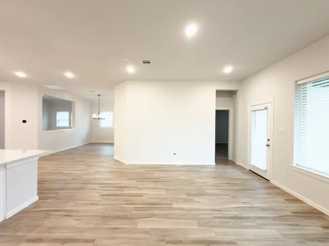 a view of an empty room with wooden floor and windows