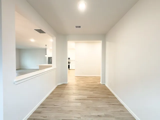 a view of a hallway with wooden floor and a bathroom