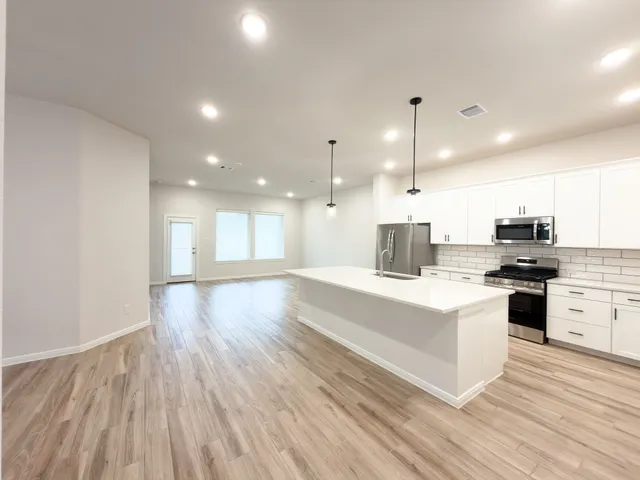 a large kitchen with kitchen island a stove a sink dishwasher and a refrigerator with wooden floor