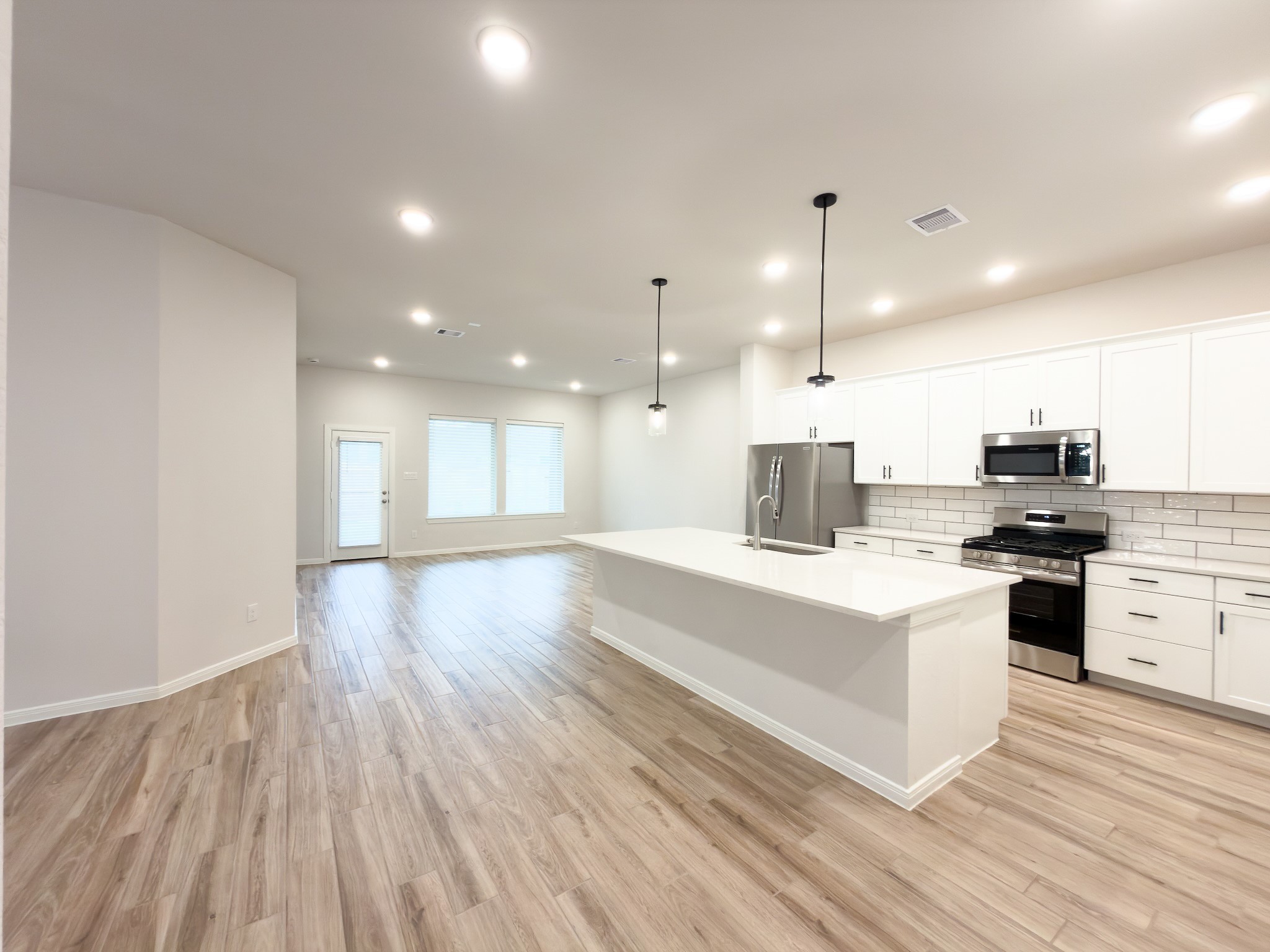42504 Rustico Road Magnolia, TX 77354 - Photo 3 of 46 a large kitchen with kitchen island a stove a sink dishwasher and a refrigerator with wooden floor