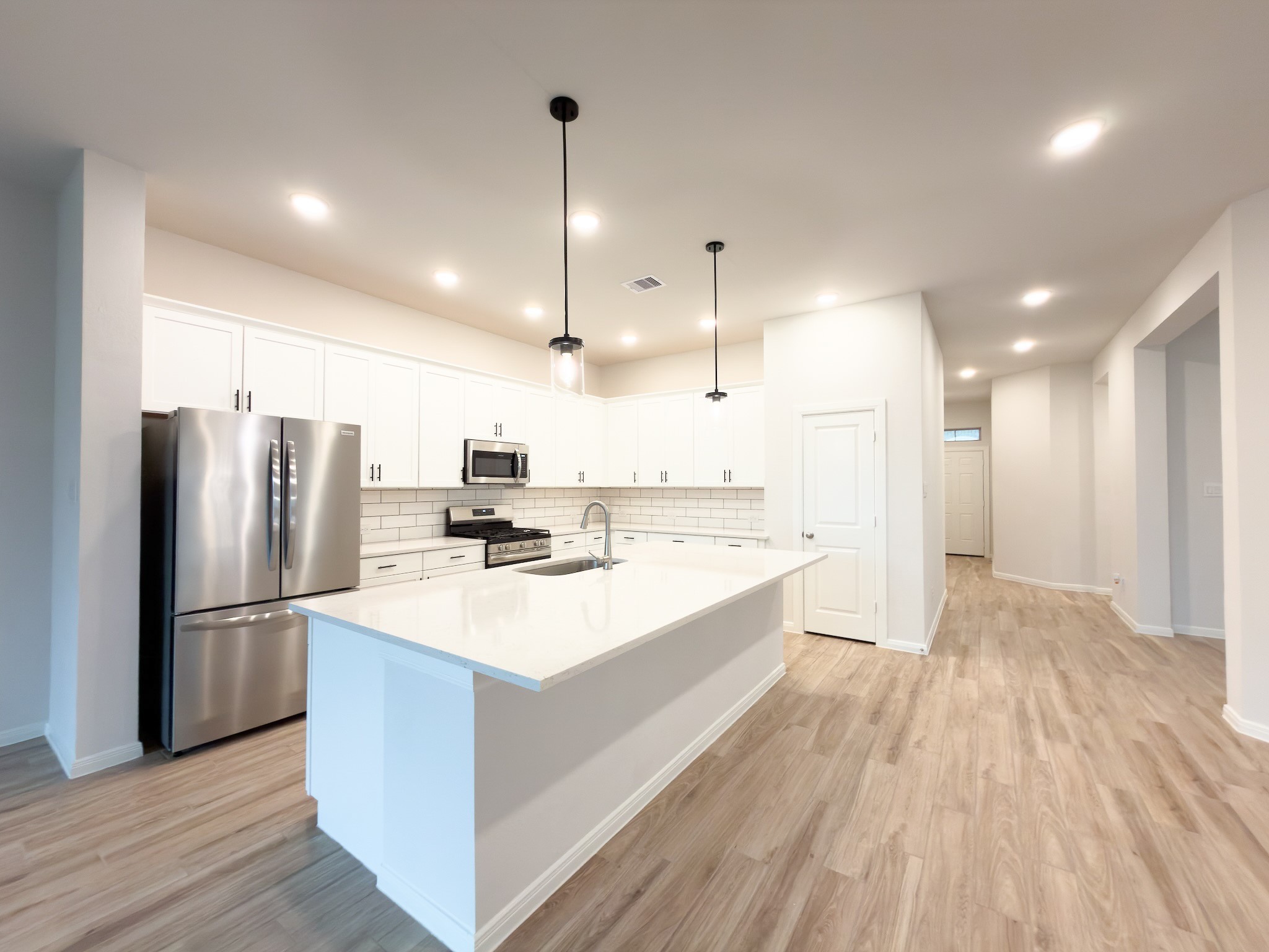 42504 Rustico Road Magnolia, TX 77354 - Photo 4 of 46 a large kitchen with kitchen island a refrigerator a stove a sink dishwasher with wooden floor