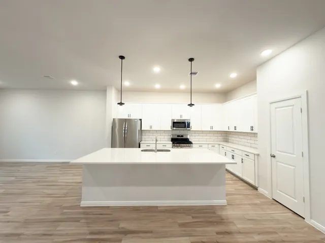 a large white kitchen with wooden floor