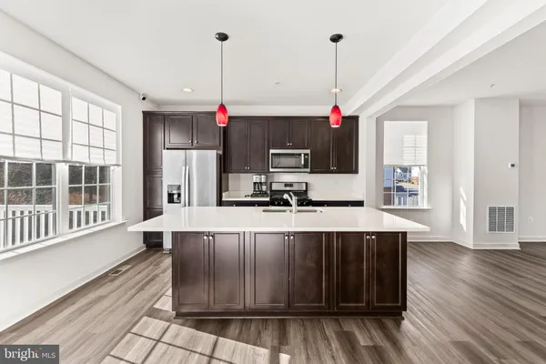 a kitchen with stainless steel appliances granite countertop a stove a sink dishwasher a microwave oven and a refrigerator with wooden floor
