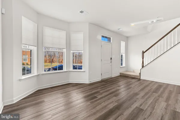 a view of an empty room with wooden floor and stairs