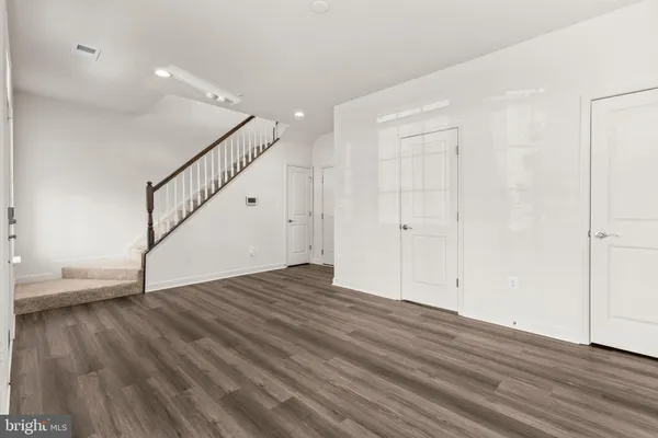 a view of an empty room with wooden floor and stairs