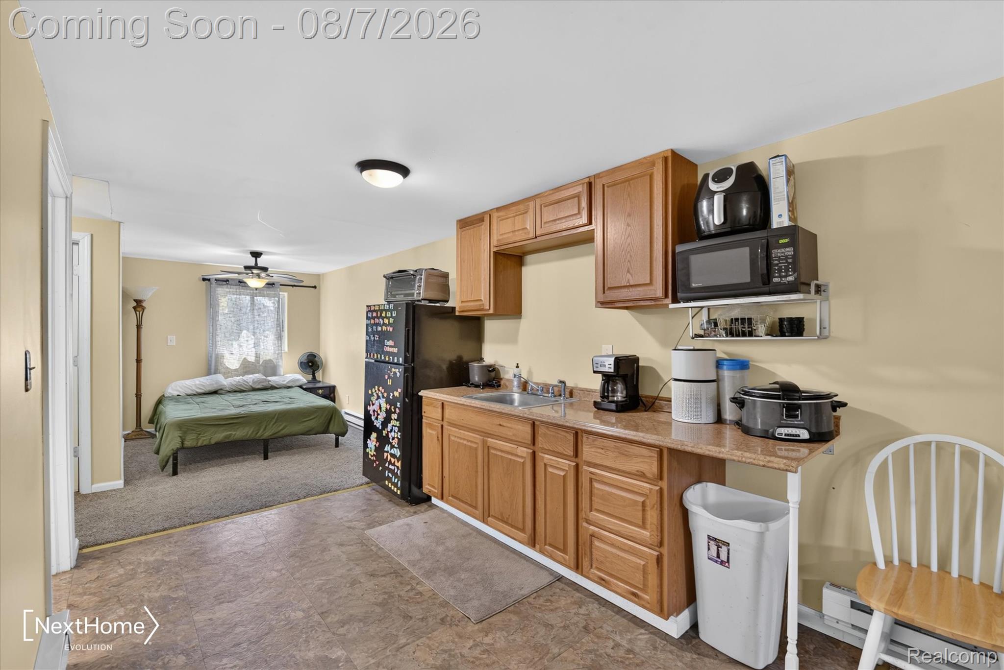 23740 Carleton West Road Belleville, MI 48111 - Photo 47 of 58 Open-concept living space featuring warm wood cabinetry with ample storage, stainless steel appliances including a refrigerator and microwave, tile flooring, and pendant lighting