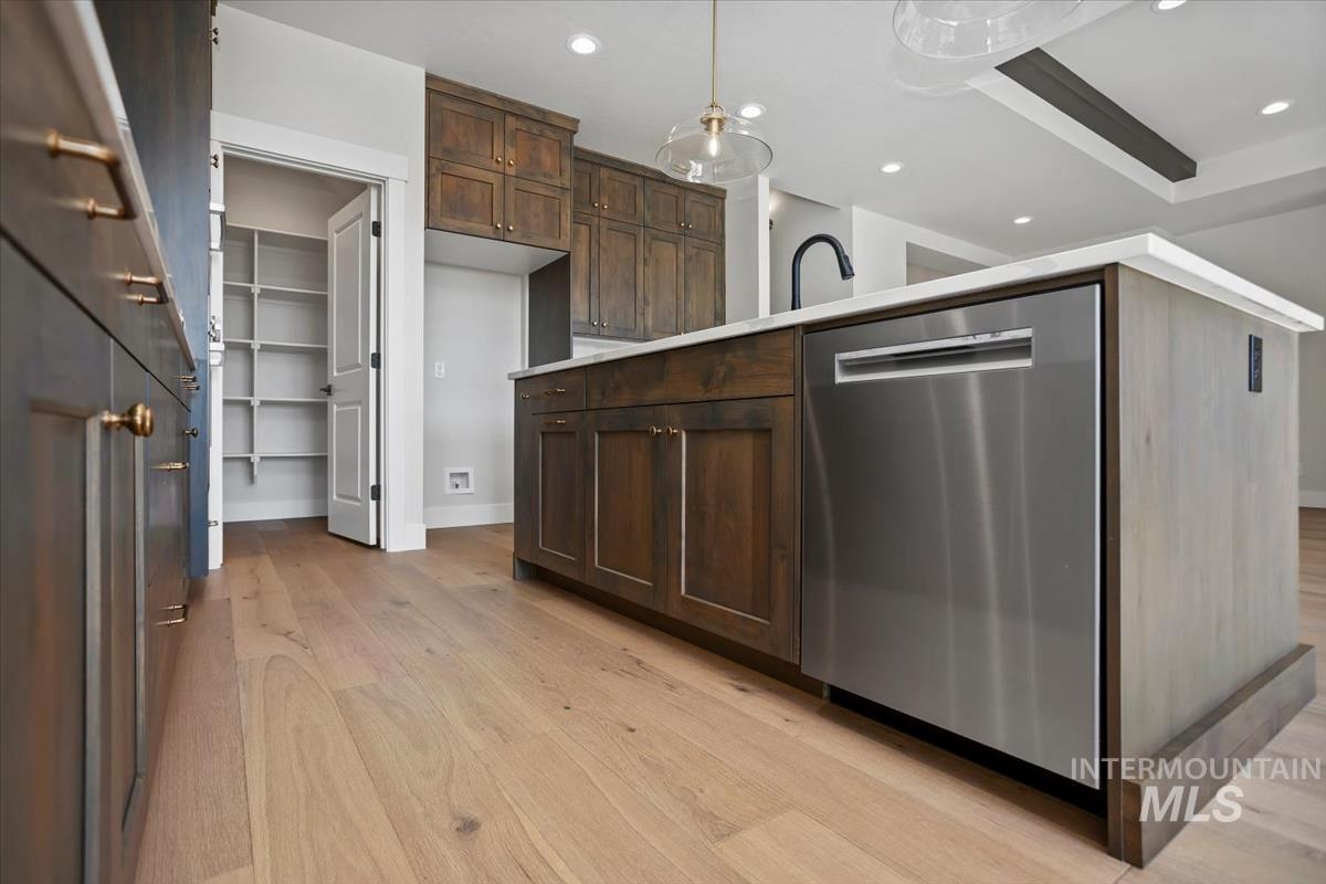 232 South Fusion Avenue Kuna, ID 83634 - Photo 12 of 50 Kitchen featuring dishwasher, dark wood finish cabinetry, light wood-type flooring, light countertops, and decorative light fixtures