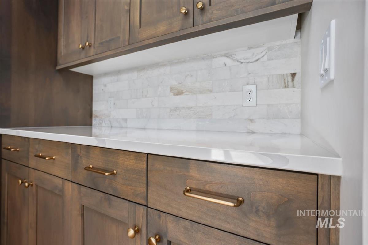 232 South Fusion Avenue Kuna, ID 83634 - Photo 14 of 50 Detailed view of dark wood finish cabinets, backsplash, and light stone counters