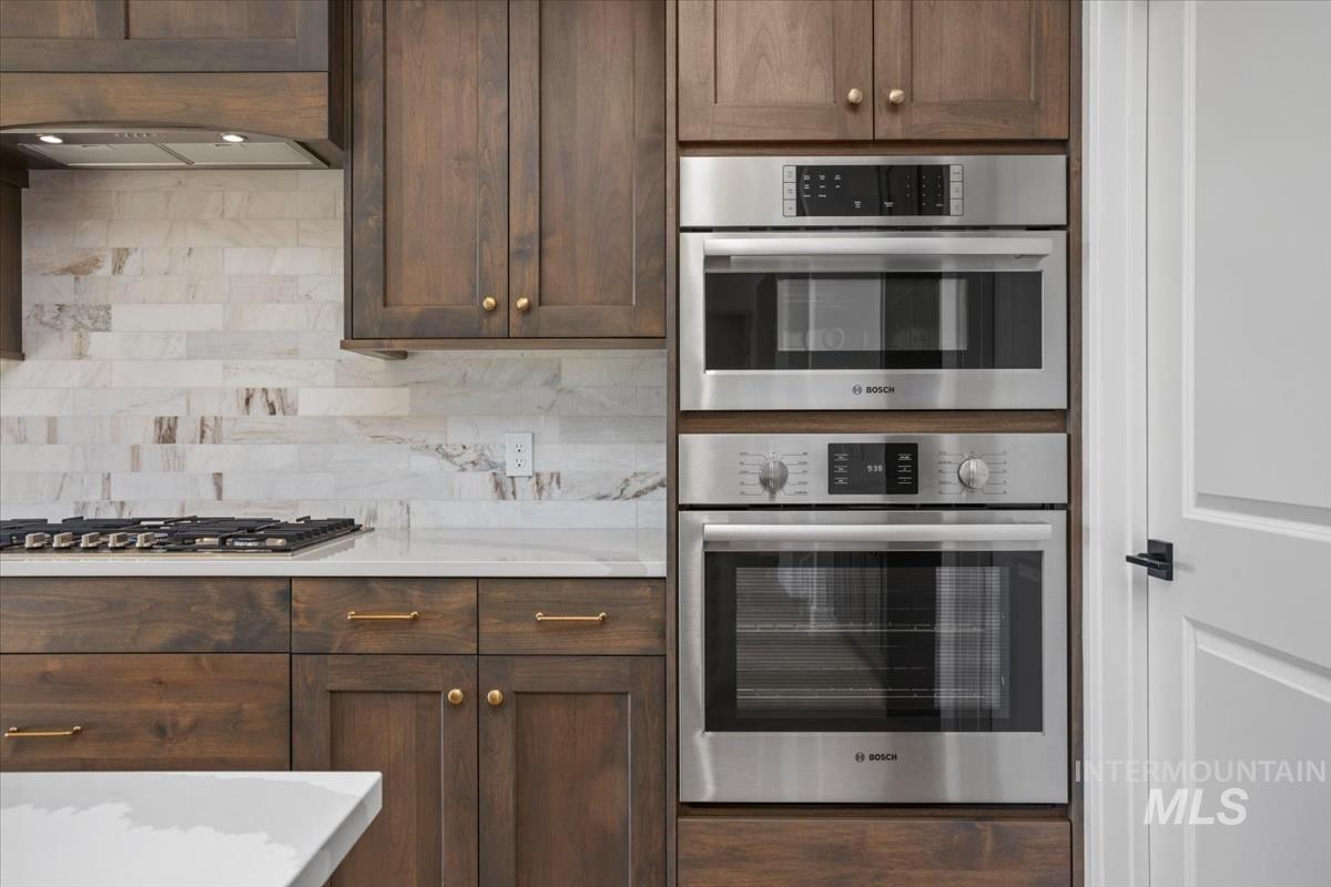 232 South Fusion Avenue Kuna, ID 83634 - Photo 15 of 50 Kitchen with stainless steel appliances, dark wood finish cabinetry, light stone countertops, and tasteful backsplash