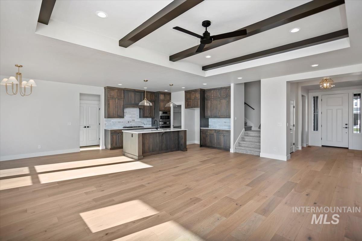 232 South Fusion Avenue Kuna, ID 83634 - Photo 49 of 50 Kitchen with suspended lighting, beam ceiling, open floor plan, dark wood finish cabinets, and light wood-type flooring