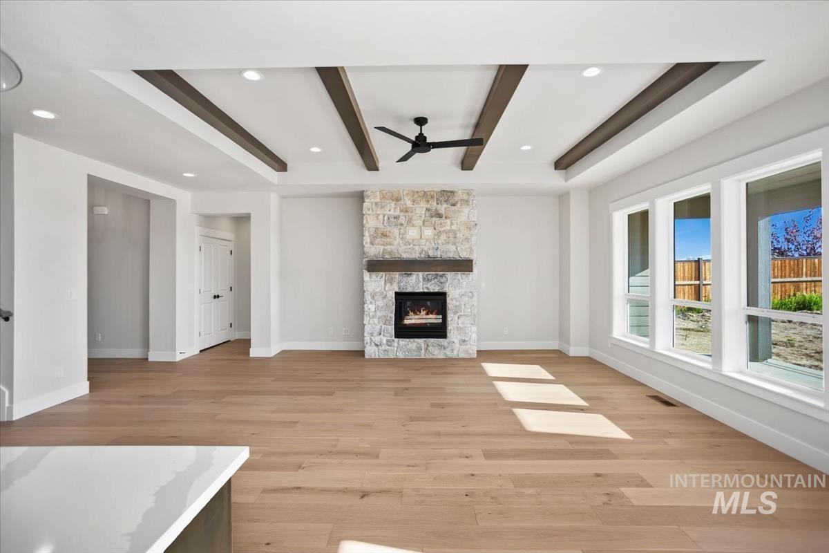 232 South Fusion Avenue Kuna, ID 83634 - Photo 20 of 50 Unfurnished living room with light wood-style flooring, recessed lighting, a fireplace, beam ceiling, and ceiling fan
