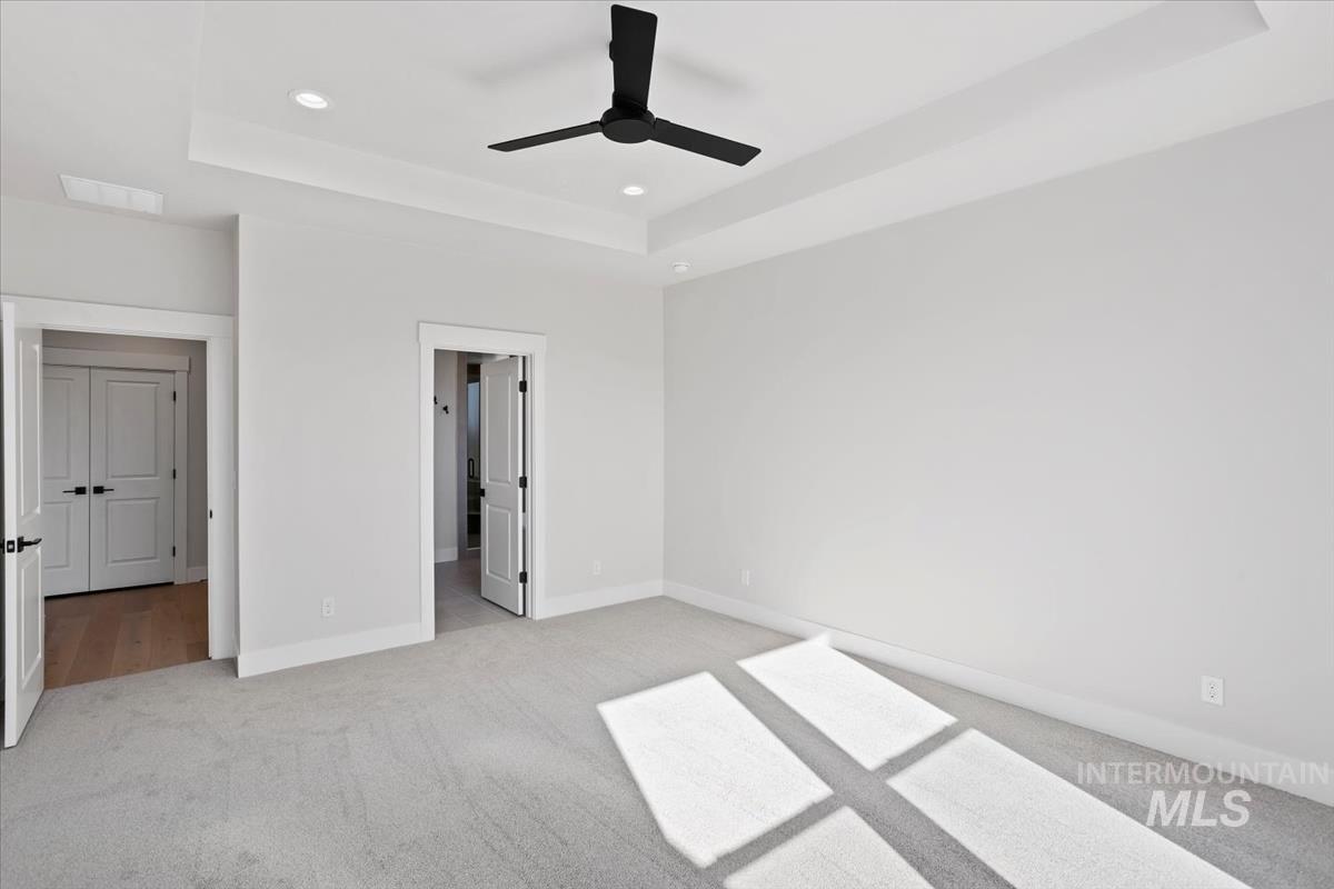 232 South Fusion Avenue Kuna, ID 83634 - Photo 23 of 50 Unfurnished bedroom featuring a tray ceiling, light carpet, a ceiling fan, and recessed lighting