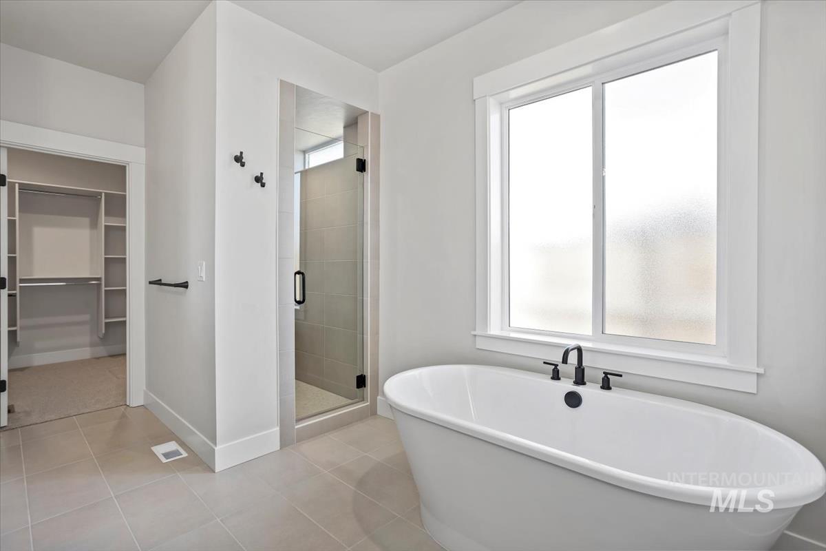 232 South Fusion Avenue Kuna, ID 83634 - Photo 27 of 50 Full bathroom with a spacious closet, a stall shower, a soaking tub, and light tile patterned floors
