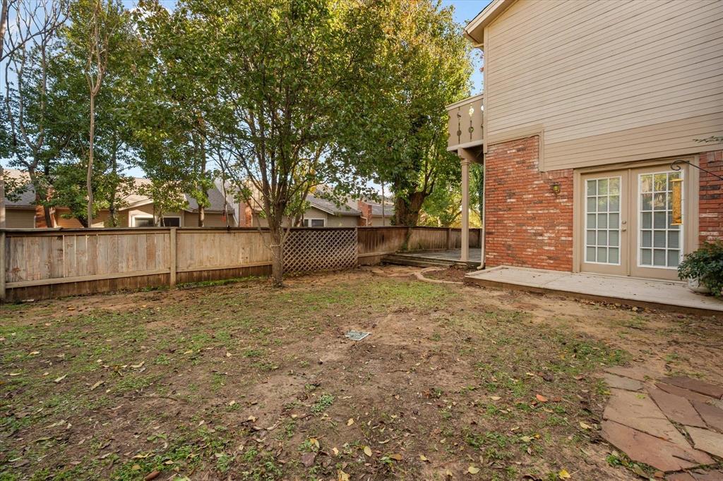 2312 Perkins Road Arlington, TX 76016 - Photo 24 of 29 Private backyard featuring mature trees, a wooden privacy fence, and a flagstone path