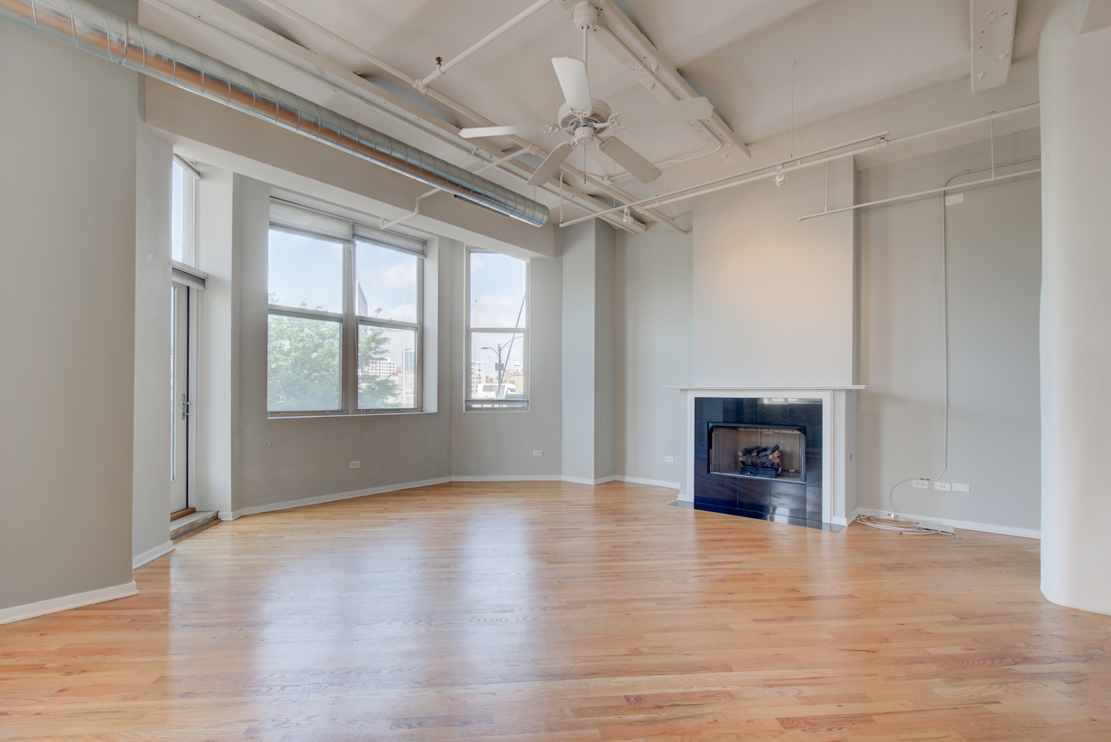 500 South Clinton Street, Unit 230 Chicago, IL 60607 - Photo 4 of 31 an empty room with wooden floor a fireplace and windows