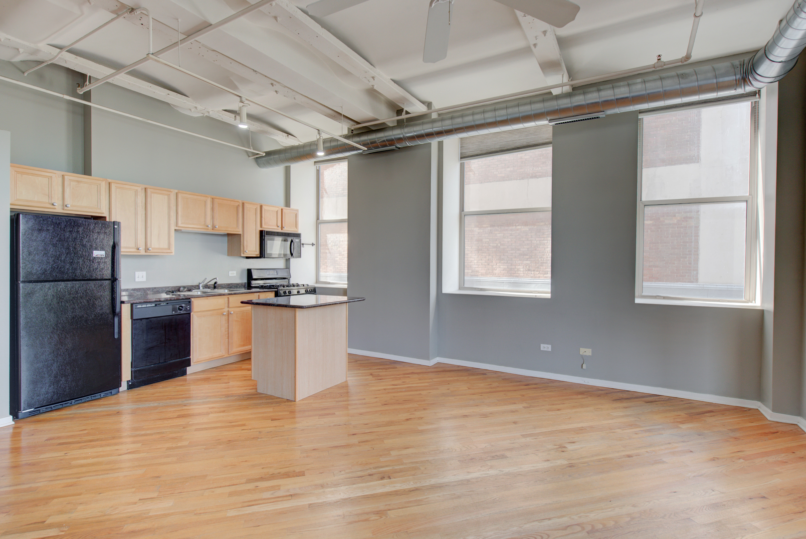 500 South Clinton Street, Unit 230 Chicago, IL 60607 - Photo 7 of 31 a kitchen with granite countertop a refrigerator and wooden cabinets