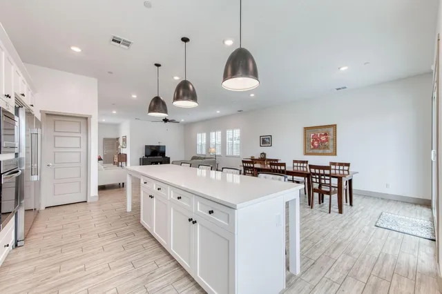 a large kitchen with stainless steel appliances a large center island a stove a refrigerator and a view of living room