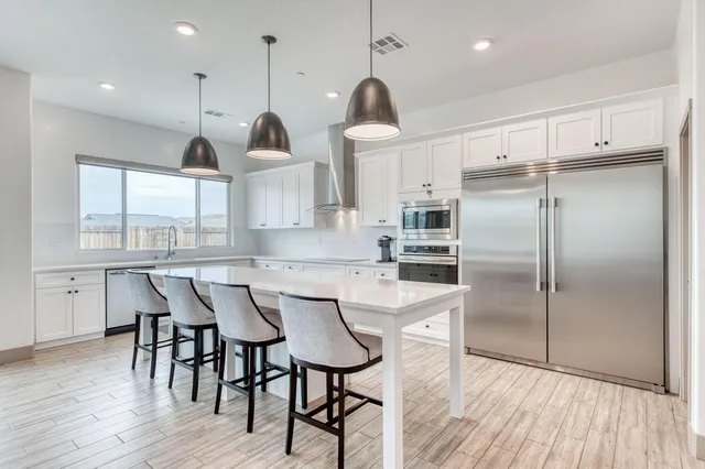 a kitchen with stainless steel appliances granite countertop a kitchen island hardwood floor and a sink
