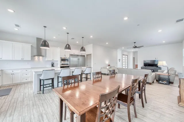 an open kitchen with kitchen island a dining table and chairs with wooden floor