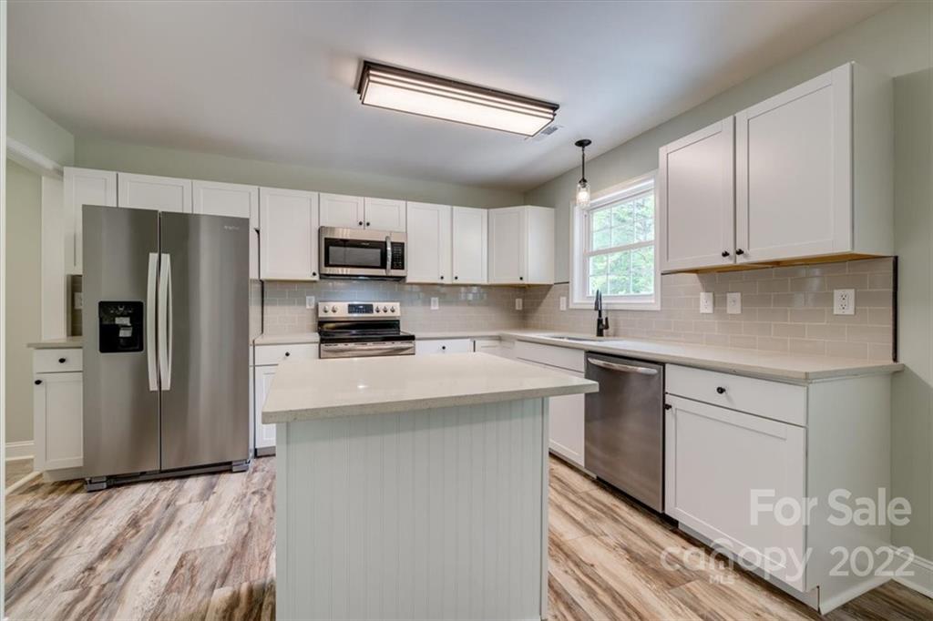 6973 Narrow Lane Road Hickory Grove, SC 29717 - Photo 11 of 35 a kitchen with stainless steel appliances granite countertop a refrigerator stove a sink and dishwasher with wooden floor