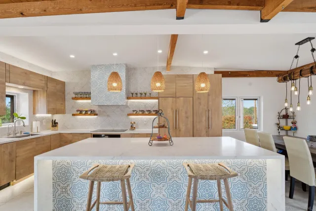 a kitchen with stainless steel appliances kitchen island granite countertop a table chairs stove and white cabinets