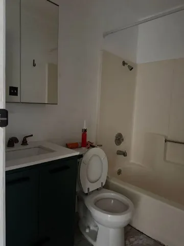 a bathroom with a granite countertop toilet sink and mirror