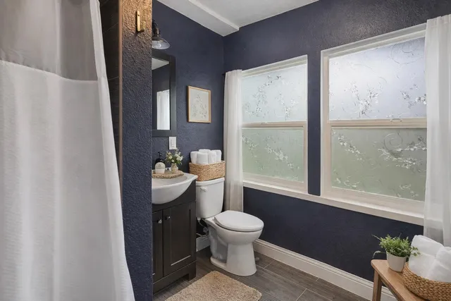 a bathroom with a granite countertop toilet a sink and a large mirror