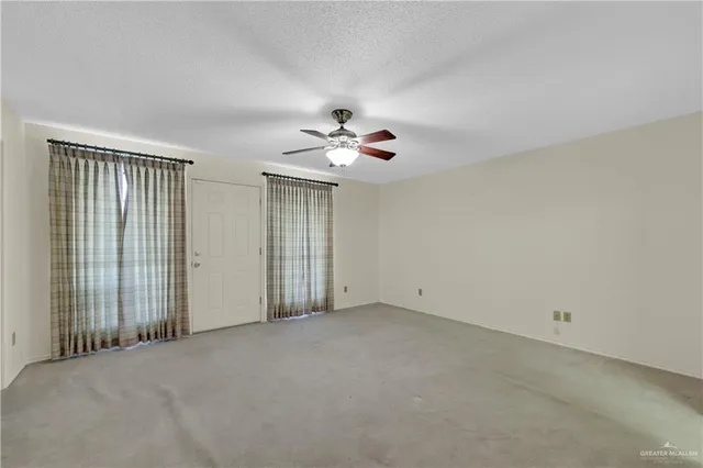 an empty room with fan and windows