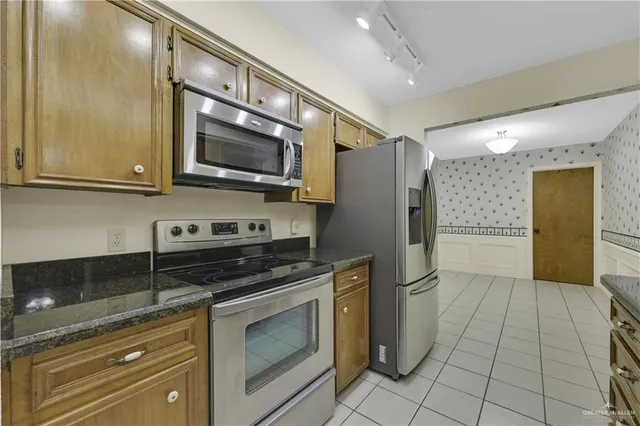 a kitchen with stainless steel appliances granite countertop a refrigerator and a stove top oven