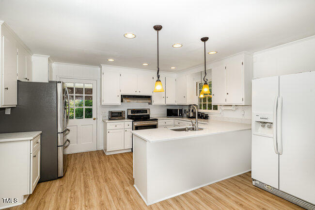 3610 Randolph Road Durham, NC 27705 - Photo 4 of 29 a kitchen with a refrigerator a stove top oven a sink dishwasher and a dining table with wooden floor
