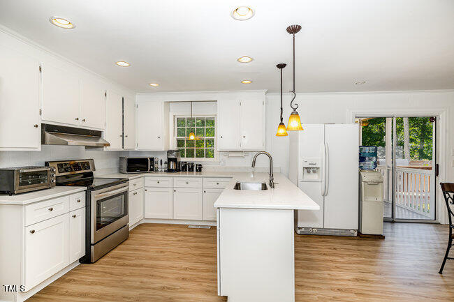 3610 Randolph Road Durham, NC 27705 - Photo 5 of 29 a kitchen with stainless steel appliances kitchen island granite countertop a sink a stove a refrigerator and white cabinets with wooden floor