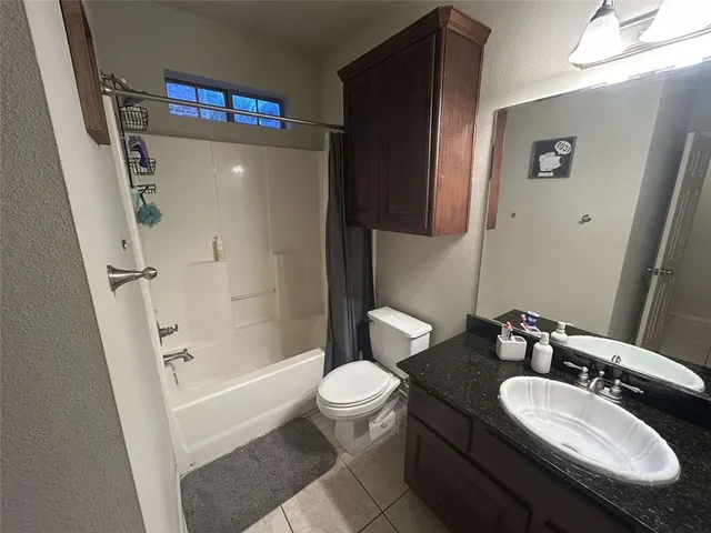 a bathroom with a granite countertop sink a toilet a mirror and shower