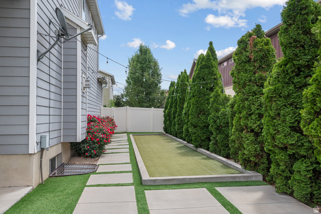955 Delorean Lane Midvale, UT 84047 - Photo 44 of 47 Backyard featuring a built-in bocce ball court with artificial turf, bordered by evergreen trees