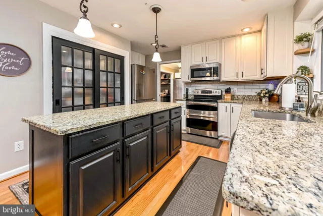 a dining hall with stainless steel appliances granite countertop a stove top oven a dining table and chairs