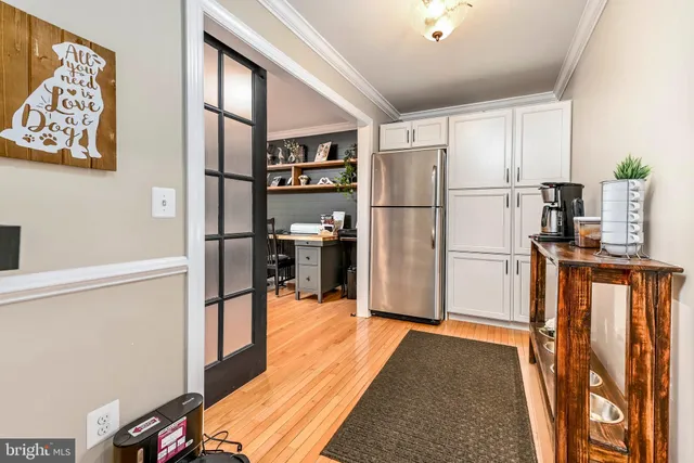 a kitchen with stainless steel appliances granite countertop a refrigerator a sink dishwasher a oven with white cabinets and wooden floor