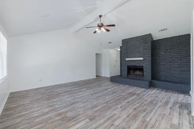 a view of empty room with wooden floor and fireplace