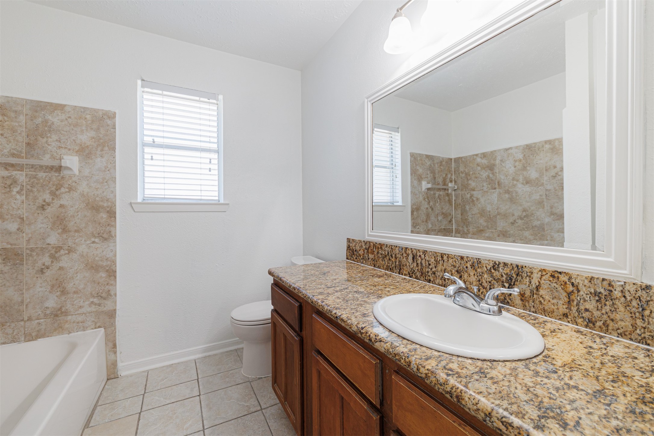 16702 Pebbleglen Drive Houston, TX 77095 - Photo 10 of 17 a bathroom with a granite countertop sink and a mirror