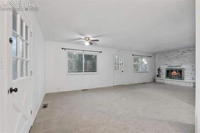 an empty room with windows and fireplace