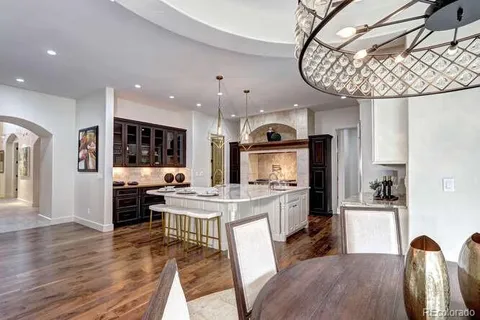 a kitchen with stainless steel appliances a dining table chairs stove and cabinets