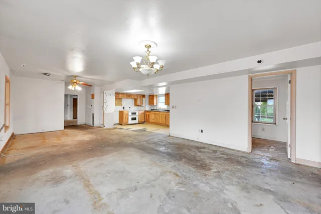 an empty room with windows and ceiling fan