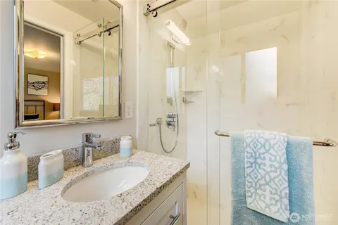 a bathroom with a granite countertop sink a mirror and shower