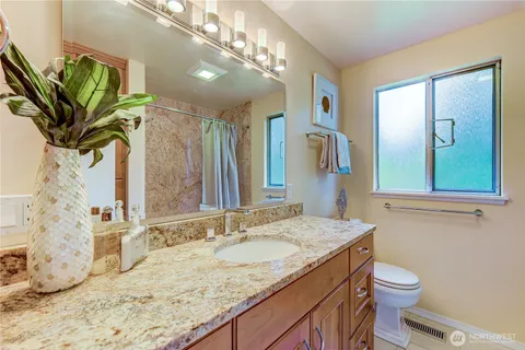 a bathroom with a granite countertop sink a toilet and a mirror