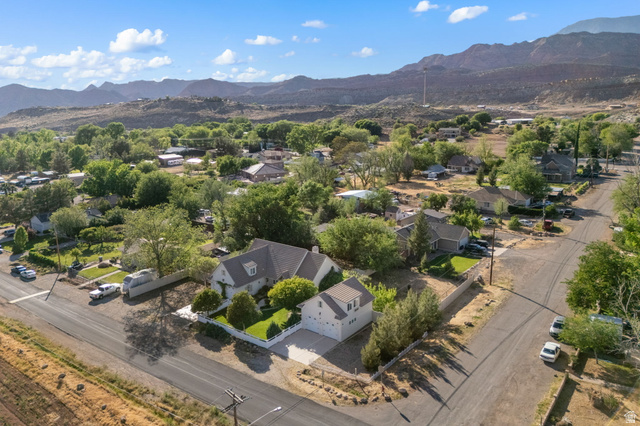 20 Valley Road Leeds, UT 84746 - Photo 49 of 57 Expansive aerial perspective showcasing a residential property with a white picket fence, mature trees, a detached garage, and mountain terrain in the background