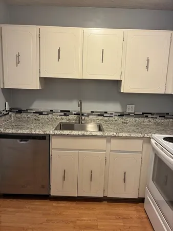 a kitchen with granite countertop white cabinets and white appliances