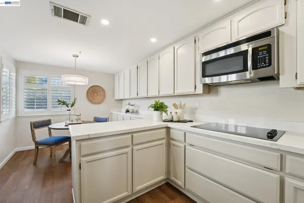 a kitchen with stainless steel appliances a dining table chairs and wooden floor