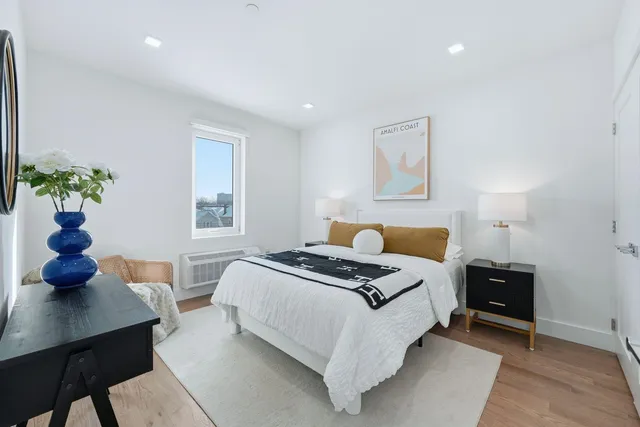 a bedroom with a bed table chair and a window