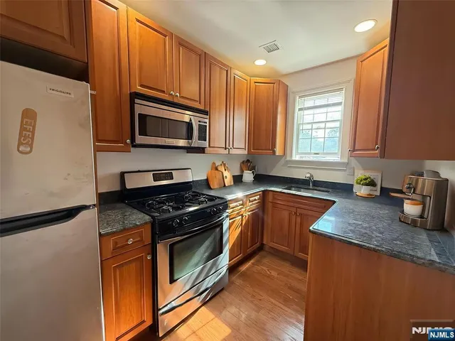 a kitchen with granite countertop wooden cabinets stainless steel appliances and a window