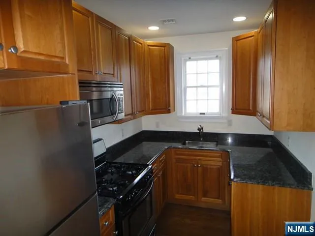 a kitchen with granite countertop a sink stove and refrigerator
