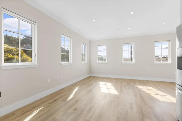 an empty room with wooden floor and windows