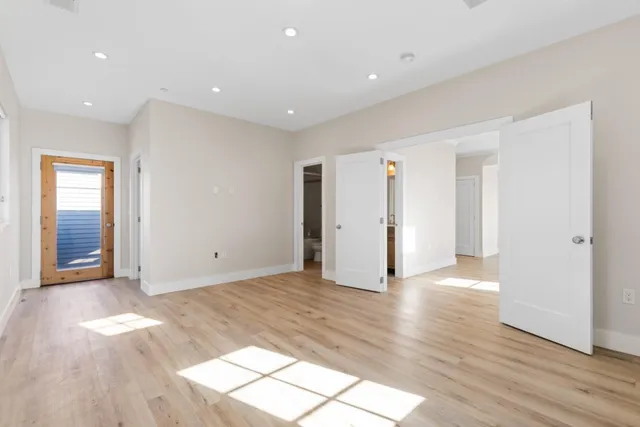 a view of an empty room with closet and wooden floor